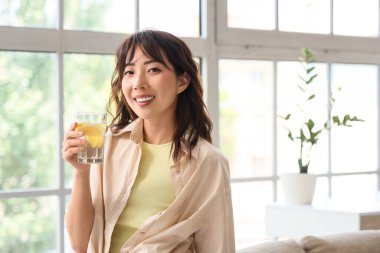 Evde limonlu su içen Asyalı genç bir kadın.