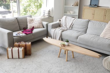 Oturma odasının içinde mayo, kanepe ve sörf tahtası var.