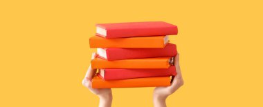 Sarı arka planda kitapları tutan eller