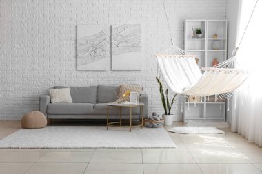 Hamağı, gri kanepesi ve kahve masası olan aydınlık oturma odasının içinde.