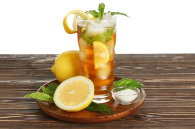 Bir bardak limonlu buzlu çay ve beyaz arka plana karşı ahşap masada nane.