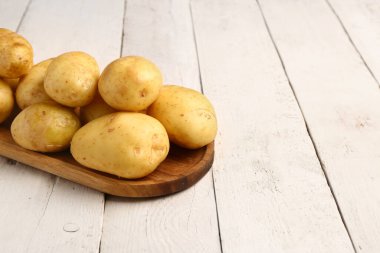 Beyaz ahşap arka planda çiğ patates tepsisi