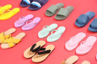 Kırmızı arkaplanda bir sürü parmak arası terlik.