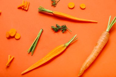 Turuncu arka planda taze havuç ve dilimler.