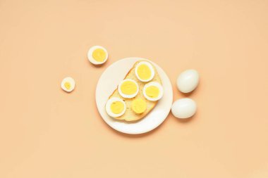 Turuncu arka planda haşlanmış yumurtalı tost.