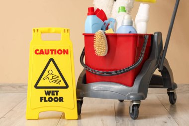 Temizlik malzemeleri ve bej duvarın yanında uyarı levhası olan bir araba.