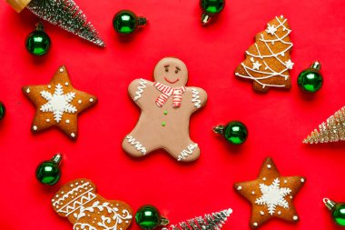 Kırmızı arka planda Noel dekoru olan zencefilli kurabiye.