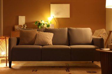 Akşamları gri kanepesi ve parlak lambaları olan modern oturma odasının içinde.