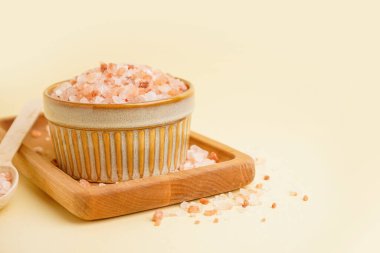Sarı arka planda Himalaya pembe tuzu olan bir kase ve ahşap tahta.