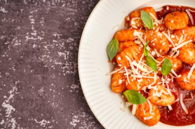 Gri arkaplanda domates soslu ve peynirli lezzetli gnocchi tabağı.