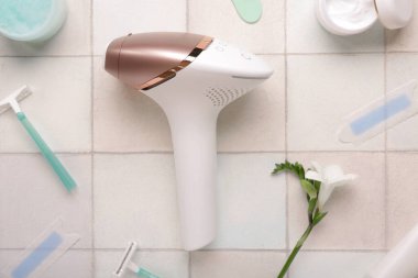 Kozmetik ürünleri, balmumu şeritleri ve beyaz fayanslı ustura ile modern fotoepilatör.