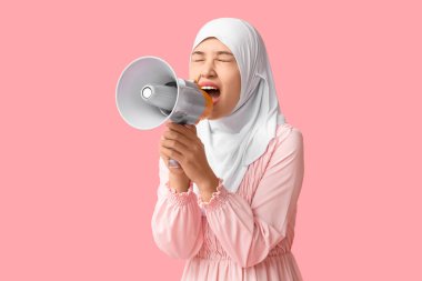 Genç Asyalı Müslüman kadın pembe arka planda megafona bağırıyor. Ulusal Duyulma Günü