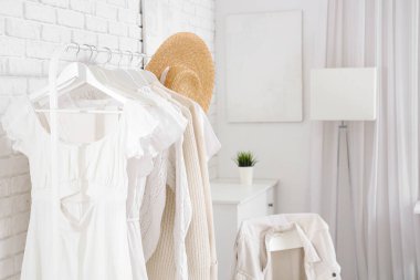 Süslü kadın giysileri açık yatak odasında askıda asılı duruyor.