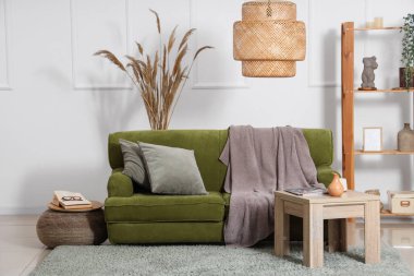 Yeşil kanepesi, masası ve otları olan rahat bir oturma odası.