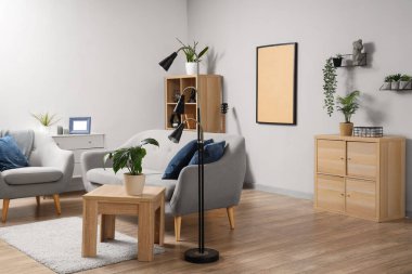 Gri kanepe, masa ve bitkilerle aydınlık oturma odasının içinde.