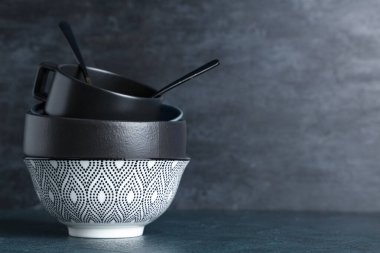 Masada siyah grunge arka planına karşı temiz sofra takımı ve çatal bıçak yığını