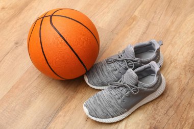 Basketbol topu ve tahta arka planda ayakkabılar.