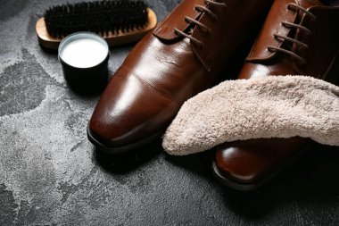 Siyah arka planda parlak deri ayakkabılar, kumaş, fırça ve ayakkabı cilası.