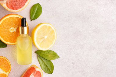 Temel yağ şişesi ve hafif arka planda taze narenciye meyvesi bileşimi