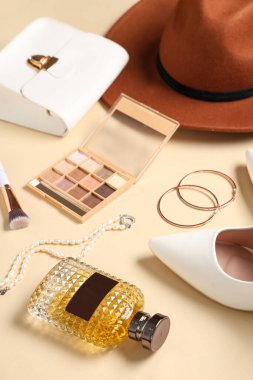 Bir şişe parfüm, göz falı, bej arka planda çanta ve aksesuarlar, yakın plan.