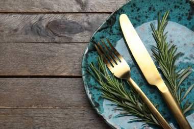 Ahşap zemin üzerinde çatal bıçak ve biberiye ile modern masa ayarları