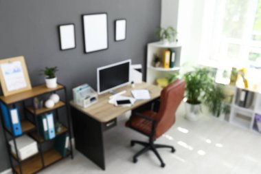 Çalışma odası, koltuk, modern bilgisayar, ev bitkisi ve raflama ünitesi, siyah duvarın yanında bulanık görünüm