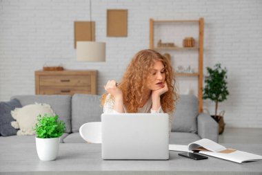 Evde dizüstü bilgisayarda yazan genç bir kadın.