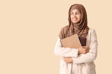 Bej arkaplan üzerine not defterleri olan Müslüman iş kadını