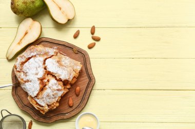 Lezzetli armutlu turta, bej ahşap arka planda taze meyve ve badem.