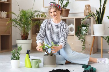 Evde yeşil bitkilerle ilgilenen genç bir kadın.