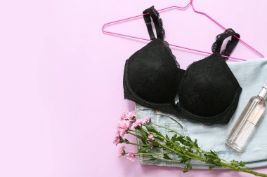 Şık kadın sütyeni, kot pantolon, parfüm şişesi ve leylak arkaplanda çiçekler.