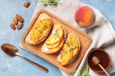 Ahşap tahta şeftali bruschetta, ricotta, keten tohumu ve mavi arka planda mikro yeşil