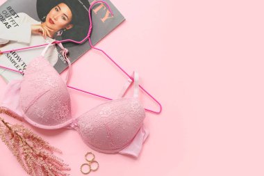 Pembe arka planda şık bayan sütyeni, dergisi ve yüzükleri olan kompozisyon