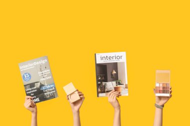 Farklı dergilere sahip kadın elleri ve sarı arka planda dekoratif kozmetik ürünler.