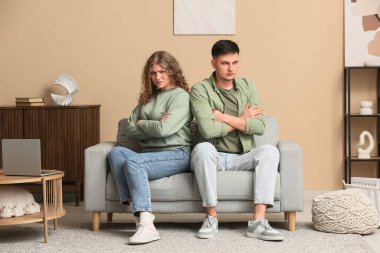 Oturma odasındaki kanepede oturan üzgün çift.