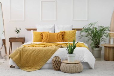 Büyük yataklı ve bitkilerli aydınlık yatak odasının içi.