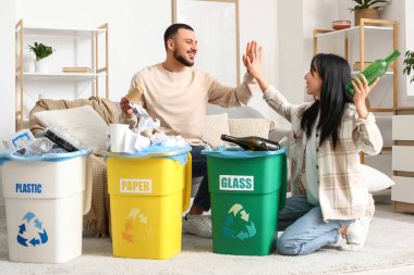 Çöpleri çöp tenekelerinde toplayan genç bir çift evde beşlik çakıyor. Küresel Geri Dönüşüm Günü