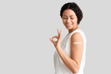 Tıbbi yaması olan genç bir Afro-Amerikalı kadın açık arkaplandaki aşıdan sonra iyi görünüyor.