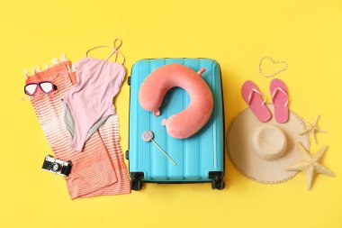 Çantalı kompozisyon, mayo ve sarı arka planda plaj aksesuarları.