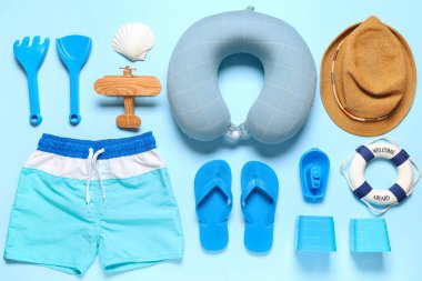 Çocuk kıyafetleri, plaj oyuncakları ve aksesuarları mavi arka planda.