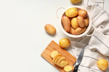 Ahşap tahta ve arka planda çiğ bebek patatesli süzgeç.