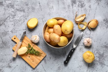 Bir kase çiğ patates, sarımsaklı ve kekik arkaplanda.