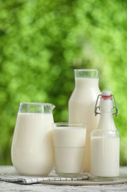 Dışarıdaki grunge masasında bardaklar ve taze süt şişeleri.