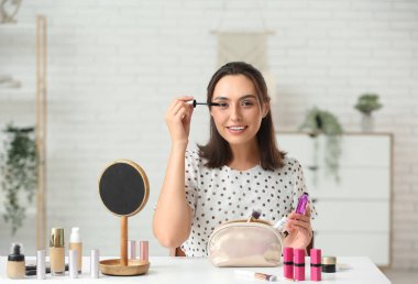 Kozmetik çantalı güzel bir kadın soyunma odasında makyaj yapıyor.