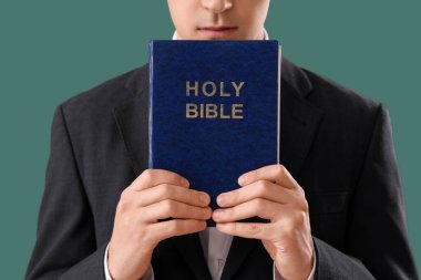 İncil 'i olan genç adam yeşil arka planda dua ediyor, yakın plan