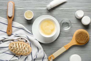 Gri ahşap arka planda farklı kozmetik ürünleri ve masaj fırçaları olan kompozisyon