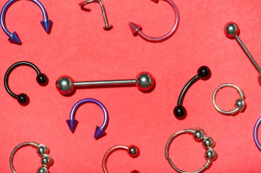 Kırmızı arka planda piercing için şık mücevherleri olan kompozisyon
