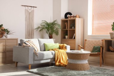 İçinde kanepe, sehpa, koltuk ve çiçek olan güzel bir oturma odası.