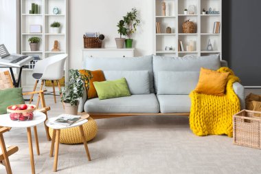 Gri kanepeli ve raf üniteli oturma odasının içi.