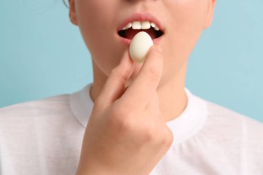 Mavi arka planda taze kaynamış bıldırcın yumurtası olan genç bir kadın, yakın plan.